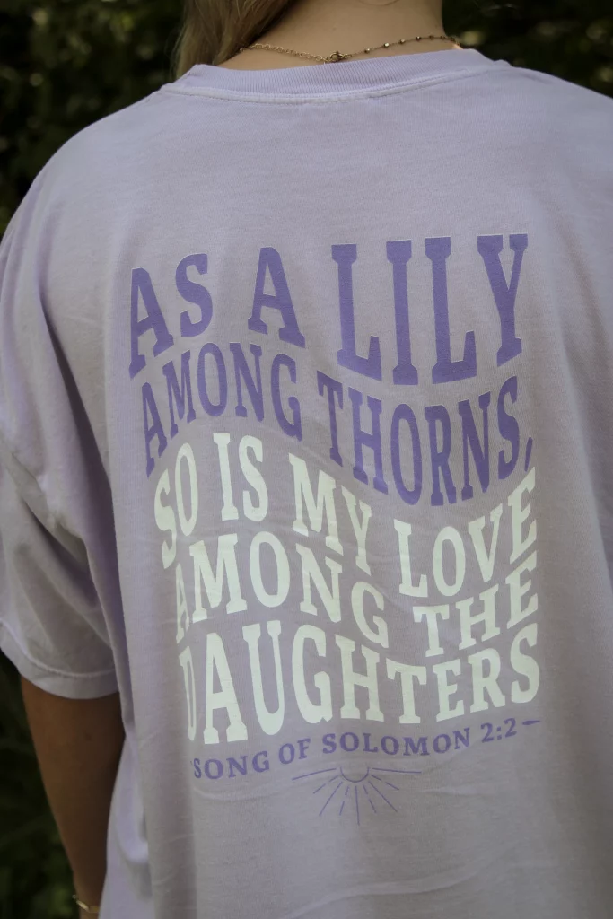 Lily Among Thorns lavender purple support tee with Song of Solomon 2:2 Bible verse on the back, an uplifting gift for domestic violence survivors.